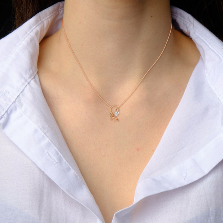 Gold necklace with a small pendant worn by a person in a white shirt.
