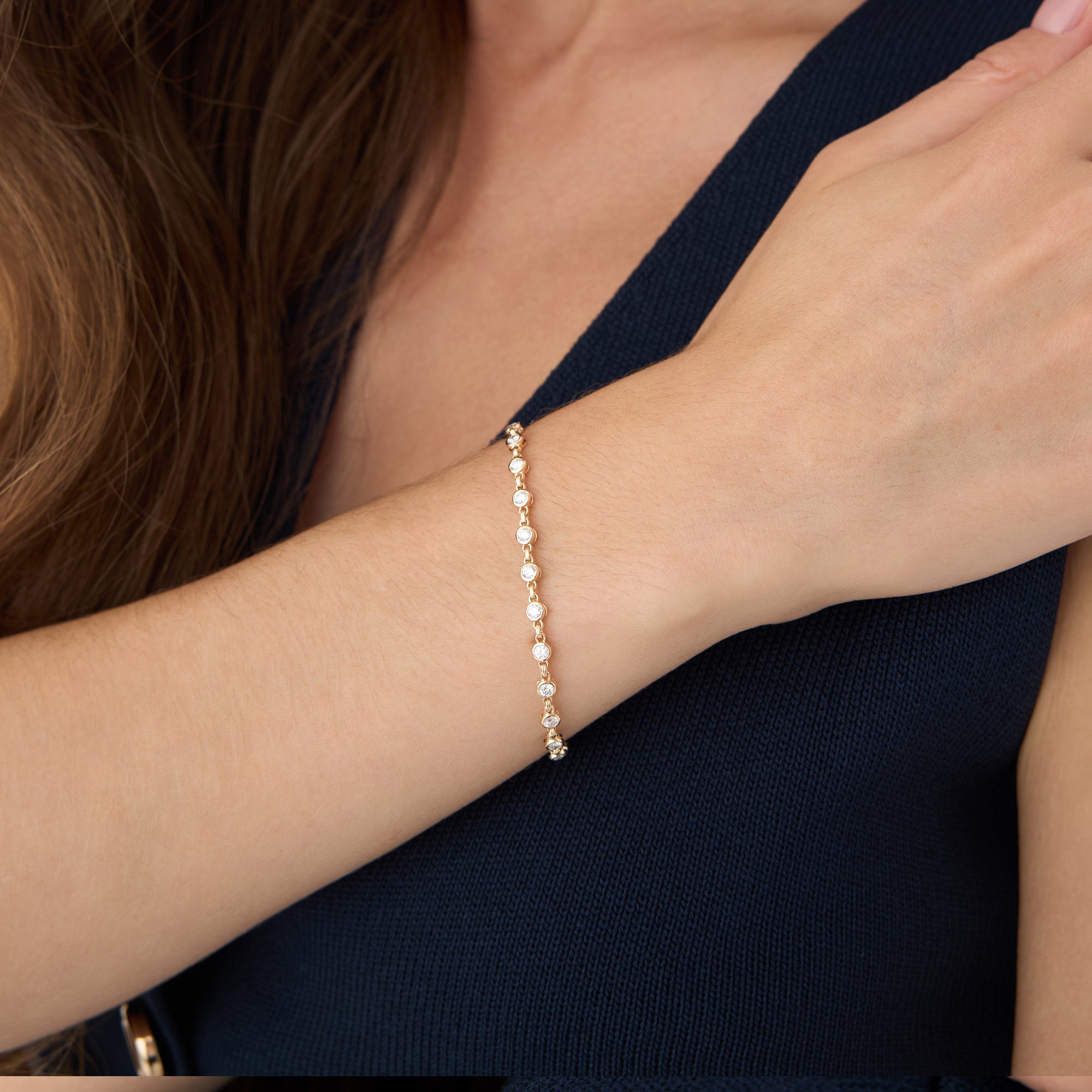 Gold bracelet on a wrist with a dark blue top