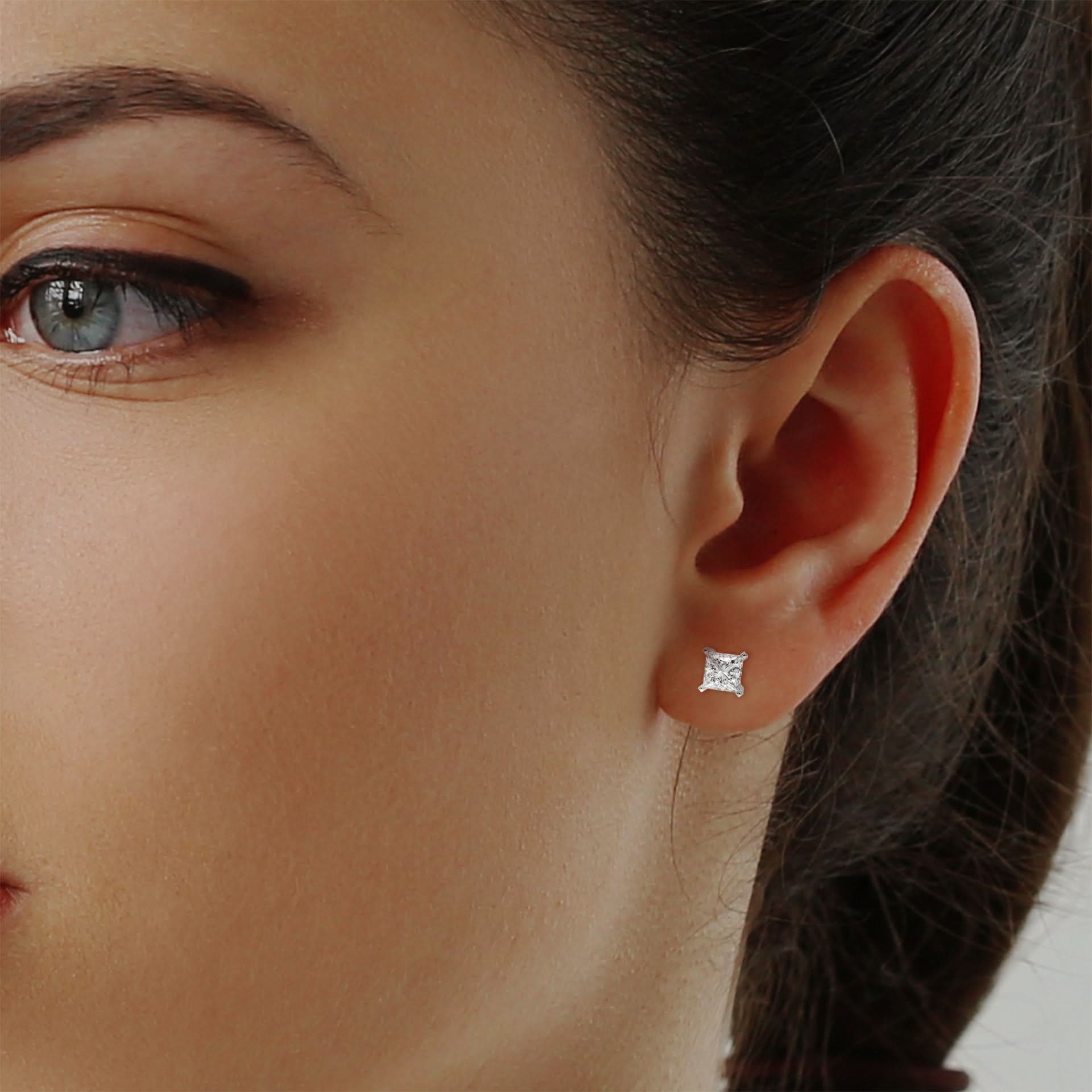 Close-up of a woman's ear wearing a diamond stud earring.