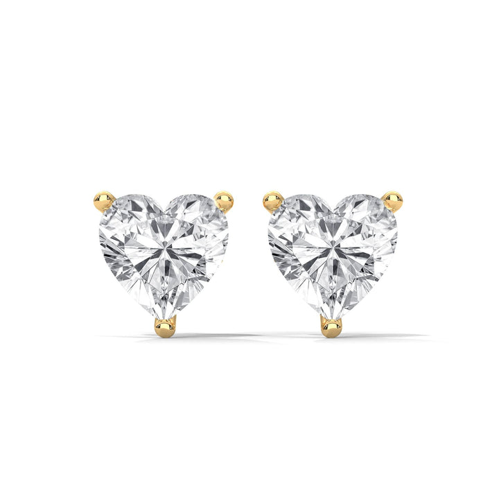Heart-shaped diamond earrings with gold prongs on a white background