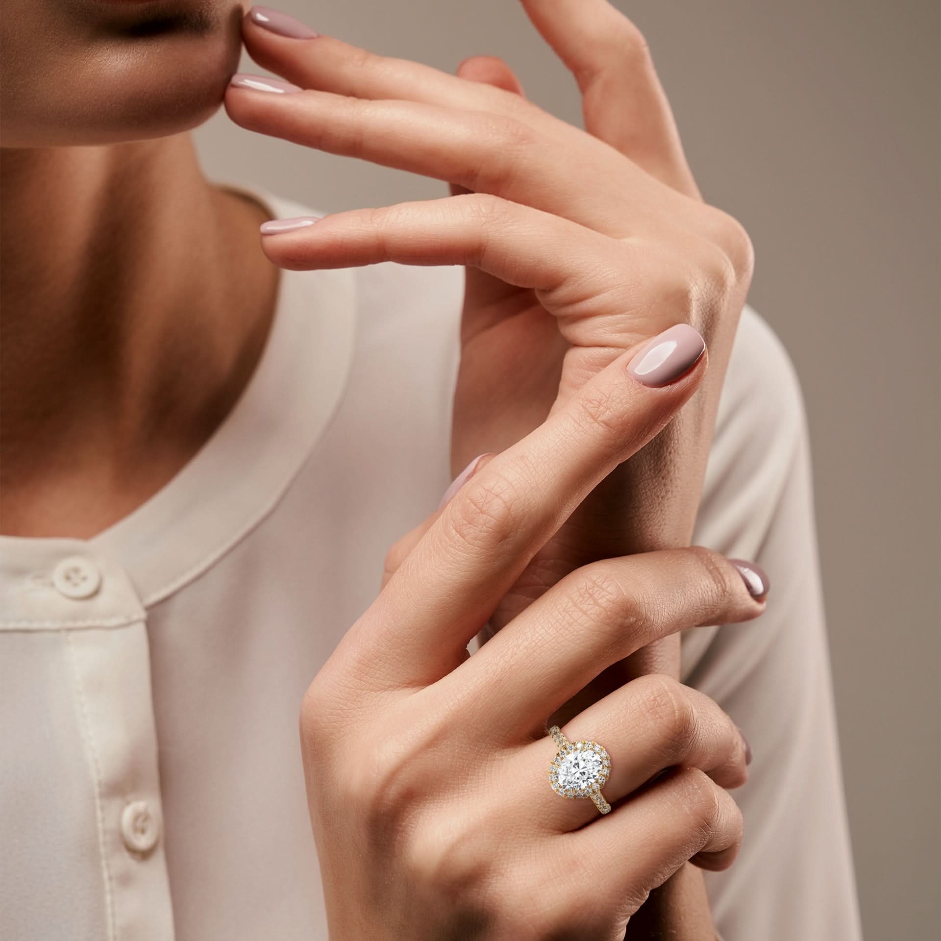 Close-up of a woman's hand wearing a Oval diamond ring on a neutral background