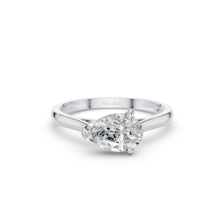 A pear-cut diamond engagement ring in a polished silver-colored metal band, shown on a clean white background with a soft shadow.