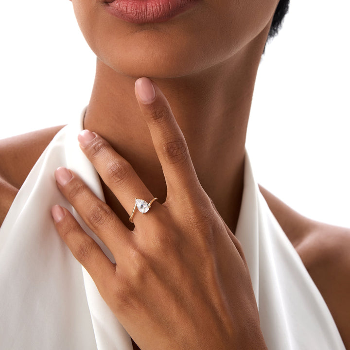 Close-up of a hand wearing an engagement ring with a white background