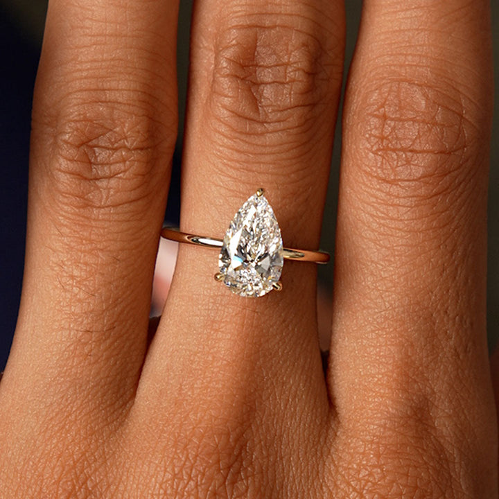 Rose gold ring with a pear-shaped diamond on a person's finger