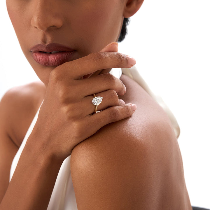 Woman wearing a diamond ring on her finger, with a blurred background