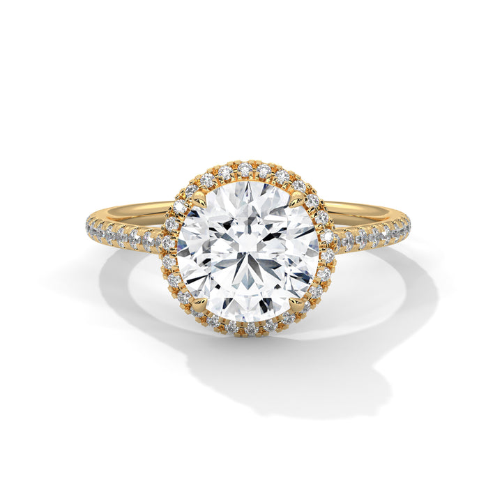 Gold ring with a large diamond and smaller diamonds on the band against a white background