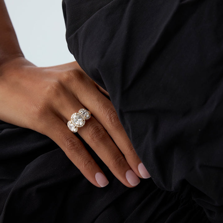 Hand wearing a diamond ring with a black garment in the background