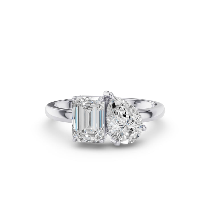 A silver engagement ring featuring an emerald-cut diamond and a round brilliant-cut diamond, set on a polished silver band against a white background.