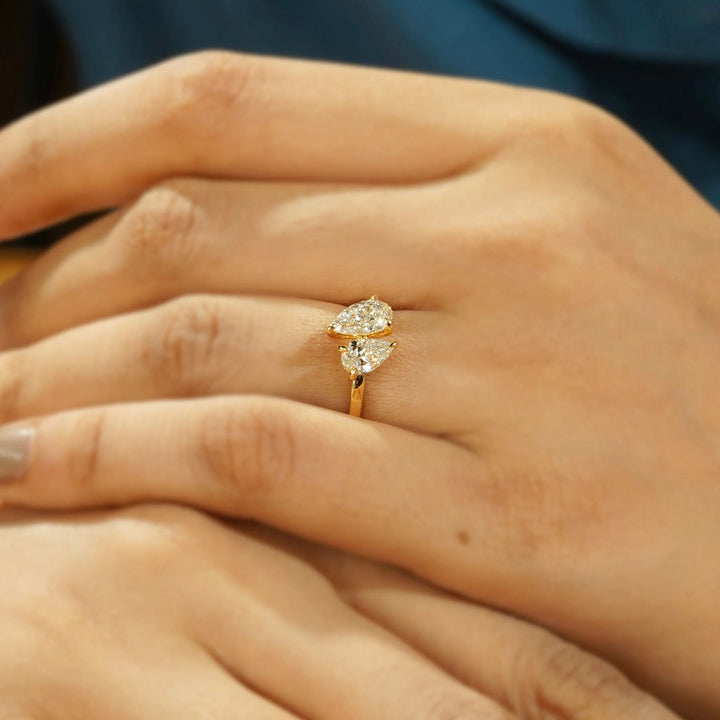 Close-up of a hand wearing a gold ring with two diamonds.